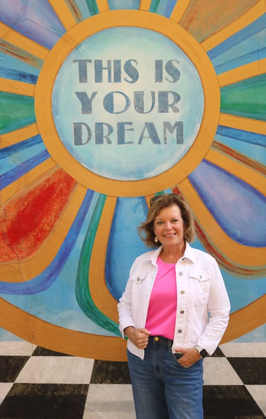 Florida Travel Advisor Sandy standing in front of a colorful “This Is Your Dream” mural.