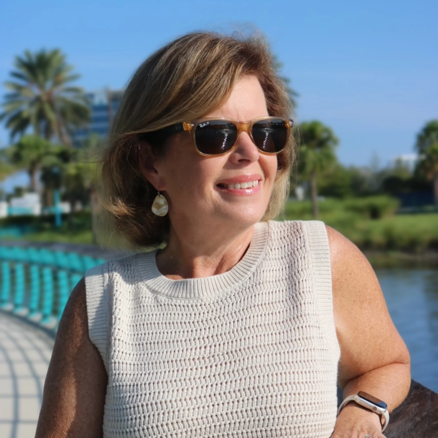 Sandy Massey, travel advisor and founder of Sandy Escapes, smiling outdoors beside the water.